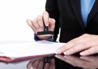 Young businesswoman (or notary public) seating at the desk in office and stamping document