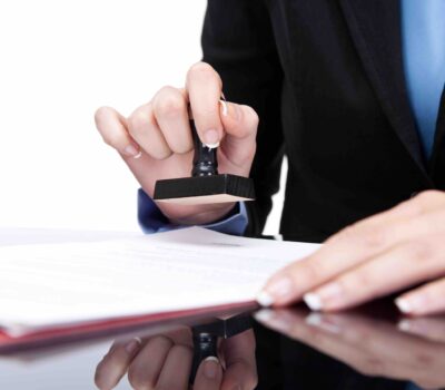 Young businesswoman (or notary public) seating at the desk in office and stamping document